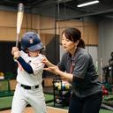 室内野球施設で打撃フォームを確認する女性コーチ